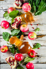 Jewish Autumn Rosh Hashana celebration. Traditional products for the celebration of Rosh Hashanah - apples with leaves, pomegranate, honey, honeycombs, white wooden  background