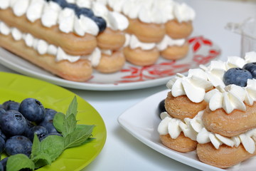 Making a cake of Italian savoiardi cookies and cream. Nearby is a plate with blueberries and mint leaves to decorate cakes.