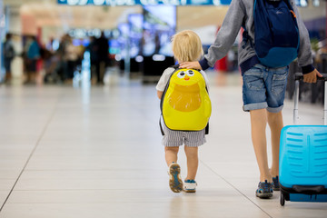 Fototapeta Sweet childre, brothers, boys, waking hand in hand at the airport, carrying suitcases and backpacks obraz