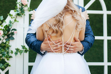 Groom and Bride embracing next to brick wall