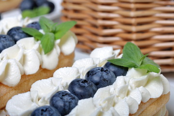 Cakes made from Italian savoyardi cookies and cream. Decorated with blueberries and mint leaves. Close up, macro shot.