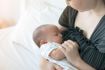 Young mother breastfeeding her newborn baby at home.