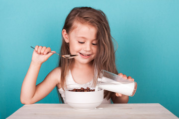 Cute little girl eating chocolate cereal with milk for breakfast