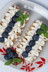 Cakes made from Italian savoyardi cookies and cream. Decorated with blueberries and mint leaves. View from above.