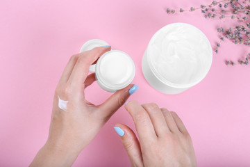 girl smears her hands cosmetic cream on the pink background. skin care, elastic and young skin of the hands. top view.