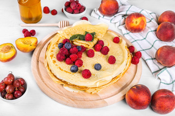 pancakes with raspberries and blueberries. Healthy summer breakfast,homemade classic russian pancakes, morning light background, copy space, top view. Stack of russian thin pancakes blini