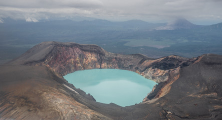 Karymsky Lake, a crater pool located in the Karymsky volcano on the Kamchatka Peninsula, Russia. Radius 5 km. Toxic gases turned this into the large acid lakes. Aquamarine blue poisonous basin. © Ingrid