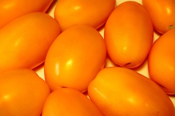 Fresh orange plum tomatoes background closeup