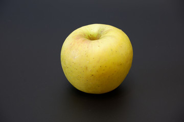 Single tasty juicy apple with shadow on dark gray background close up view