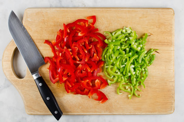 Chopped red and green bell pepper on cutting board