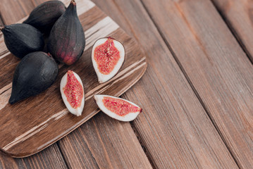 Fresh ripe figs on the brown wooden background.