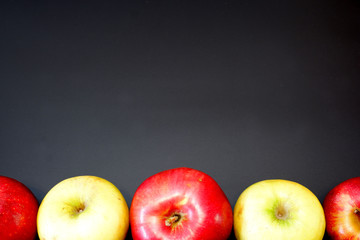 Some yellow and red apples on dark gray background close up view. Free space for custom text.