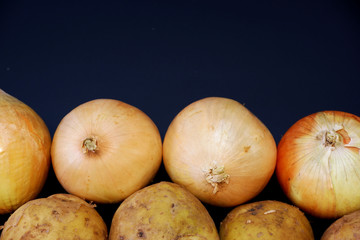 Potatoes and onions on dark gray background close up. Free space for your text.