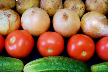Onions, tomatoes, potaoes and cucumbers on dark gray background close up