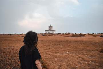 Girl looking at a lighthouse in the field II