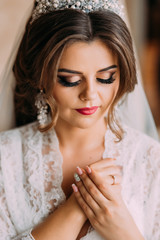 Beautiful young bride with wedding makeup and hairstyle in bedroom, newlywed woman preparation for wedding. Happy bride waiting groom. Marriage wedding day moment