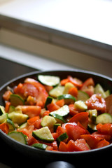 Cooking vegetables in a pan: zucchini, tomato and carrot. Selective focus.