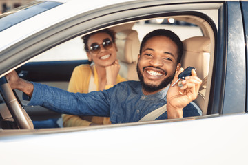 Visiting car dealership. Afro couple showing car key
