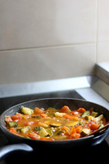 Cooking vegetables in a pan: zucchini, tomato and carrot. Selective focus.