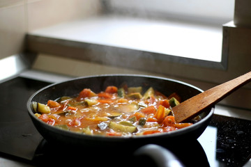 Cooking vegetables in a pan: zucchini, tomato and carrot. Selective focus.