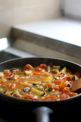 Cooking vegetables in a pan: zucchini, tomato and carrot. Selective focus.