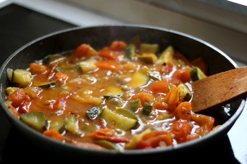 Cooking vegetables in a pan: zucchini, tomato and carrot. Selective focus.