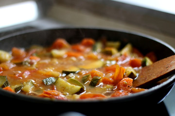 Cooking vegetables in a pan: zucchini, tomato and carrot. Selective focus.
