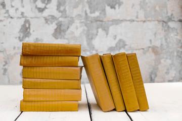 Stack of old ancient shabby books on a white wooden background.