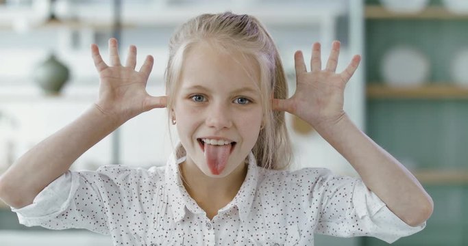 FIXED Portrait of little cute Caucasian girl doing silly funny face, looking into camera. 60 FPS Slow Motion, 4K RAW graded footage