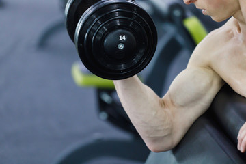 Close up view of strong man, bodybuilder exercising with dumbbells in a gym