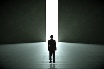 Obraz premium Businessman standing in a dark room and looking outside