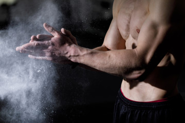 Fototapeta na wymiar Cropped shot of muscular caucasian sportsman applying talcum powder on hands