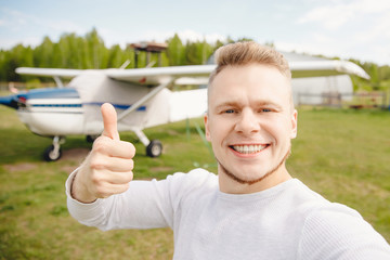 Happy tourist pilot makes selfie photo on background of plane. Concept travel by private transport © Parilov