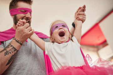 Father and daughter playing super hero and superwoman
