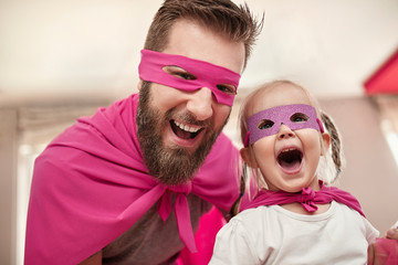 Father and daughter playing superhero and superwoman at home