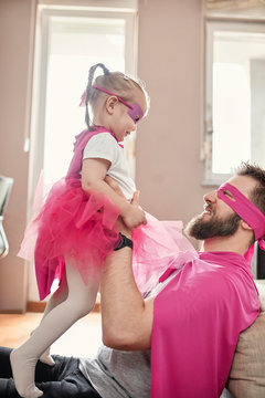 Father and daughter playing superhero and superwoman, pretending to fly