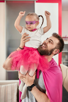 Father and daughter playing superhero and superwoman
