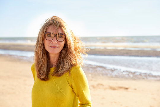 Middle Aged Woman With Frizzy Hair Walking On The Beach