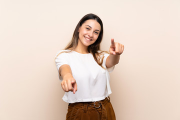 Young brunette woman over isolated background points finger at you while smiling