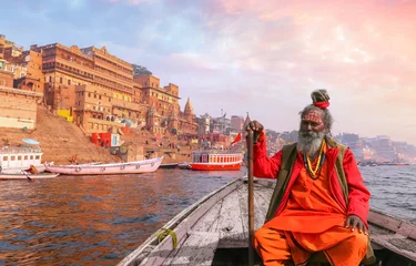 Fotobehang Indian Sadhu baba takes a boat ride on river Ganges overlooking the historic Varanasi city architecture at sunset © Roop Dey