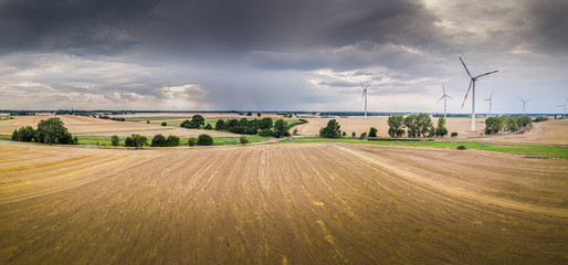 Luftaufnahme einer Landschaft bei aufziehendem Gewitter mit Windrädern