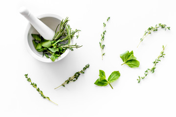 Homeopathy with leaves and healing herbs for making oil on white background top view