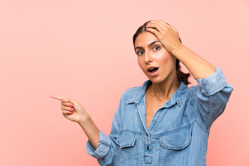 Young woman over isolated pink background surprised and pointing finger to the side