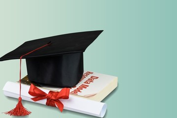 Graduation hat with tassel, diploma with red ribbon
