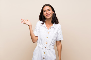 Young woman over isolated background holding copyspace imaginary on the palm to insert an ad