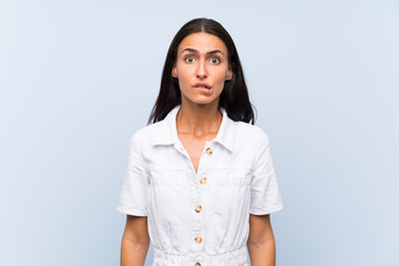 Young woman over isolated blue background having doubts and with confuse face expression