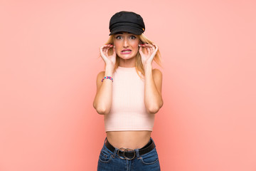 Young blonde woman with hat frustrated and covering ears