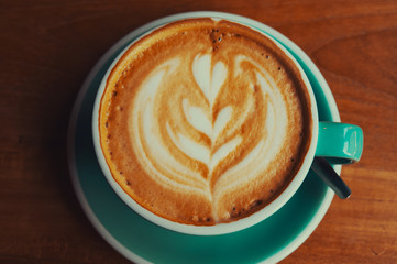 cup of coffee with cream on a wooden table 