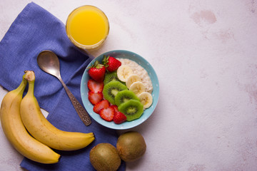 Oatmeal porridge with strawberry, banana and kiwi in bowl on background