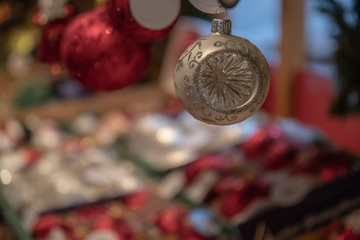 Christmas decoration. Traditional handmade matte glass white ball Christmas ornament closeup on bokeh blurred background. Holiday attribute. Christmas backdrop in red, green and white colors. New Year